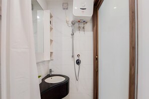 A bathroom with a black sink, white tiles, a shower, and a white toilet.