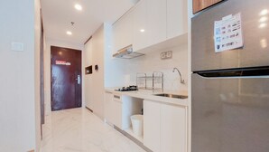 A modern kitchen with white cabinetry, a stainless steel refrigerator, and a marble floor. - Well Designed And Comfy 2Br Sky House Bsd Apartment (Pagedangan)