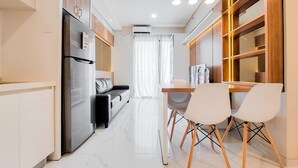 A modern kitchen with a refrigerator, dining table, and chairs. - Well Designed And Comfy 2Br Sky House Bsd Apartment (Pagedangan)