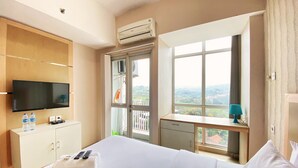 Habitación de hotel con cama, televisión, escritorio con lámpara y ventana con vistas.