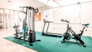 Un gimnasio con equipo de ejercicio, incluyendo una cinta de correr, bicicleta estática y máquinas de pesas.