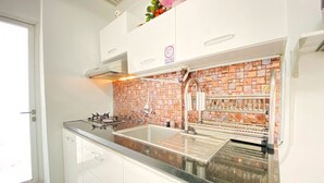 A modern kitchen with white cabinets, a stainless steel sink, and a tiled backsplash. - Comfy And Modern 2Br Apartment At Parahyangan Residence (Bandung)