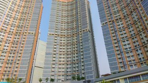 Three high-rise buildings with a modern architectural design, featuring numerous windows and a uniform facade. - Fancy Designed Studio At Gold Coast Apartment (Jakarta)
