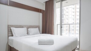 A modern hotel room with a large bed, a wooden headboard, and a view of a cityscape through a large window. - Fancy Designed Studio At Gold Coast Apartment (Jakarta)