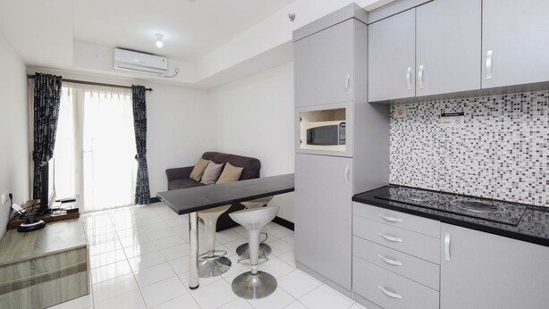 A modern kitchen with a microwave, a coffee machine, and a tiled backsplash. - Nice And Elegant 1Br At The Wave Kuningan Apartment (Jakarta)