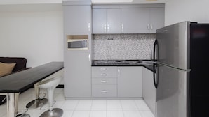 A compact kitchen with grey cabinets, a black refrigerator, and a microwave. - Nice And Elegant 1Br At The Wave Kuningan Apartment (Jakarta)