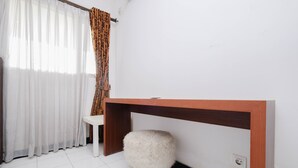A room with a white tiled floor, a wooden bench, a white fluffy stool, a wooden console table, and a window with sheer white curtains and patterned drapes. - Nice And Elegant 1Br At The Wave Kuningan Apartment (Jakarta)