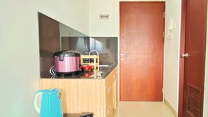 A compact kitchen with a microwave, a rice cooker, and a kettle on the counter. - Warm And Cozy Studio At Taman Melati Jatinangor Apartment (Hegarmanah)