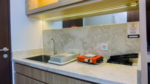 A kitchen with a sink, a scale, a toaster, and a stapler on the counter. - Minimalist And Warm Studio At Transpark Bintaro Apartment (South Tangerang)