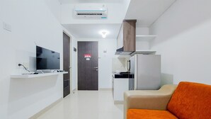 A modern hotel room with a kitchenette, a sofa, and a TV. - Luxurious 2Br At Serpong Garden Apartment (Cisauk)
