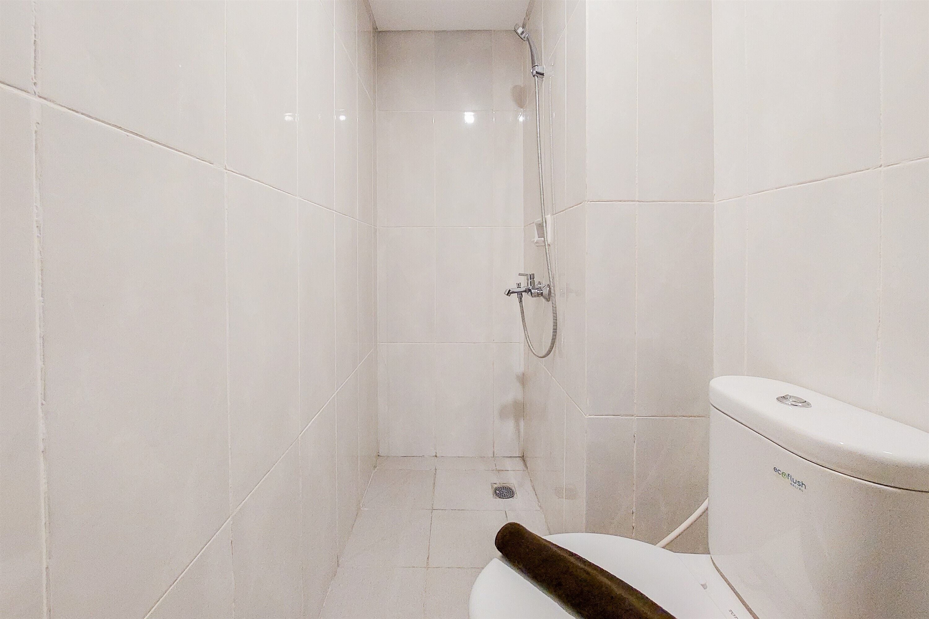 Une salle de bain avec des carreaux blancs, une douche et des toilettes.