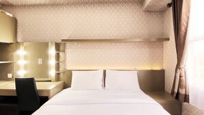 Une chambre d’hôtel avec un lit bien fait, un bureau avec une chaise et une coiffeuse avec éclairage.