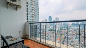 Ein Balkon mit Blick auf eine Stadtlandschaft, ein Tisch mit einem Stuhl und eine Klimaanlage.