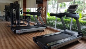 A gym with treadmills, weight machines, and a TV screen. - Pleasurable 1Br Apartment At Saveria Bsd City (Pagedangan)