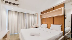 A hotel room with a large bed, a desk, a chair, and a window with curtains. - Cozy And Well Furnished 2Br At Branz Bsd City Apartment (Pagedangan)