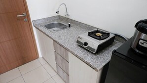 Une petite cuisine dotée d’un plan de travail en granit, d’une cuisinière à gaz, d’un évier et d’une machine à café.