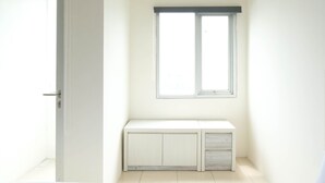 Une petite pièce lumineuse, avec un banc blanc, une fenêtre et une porte.