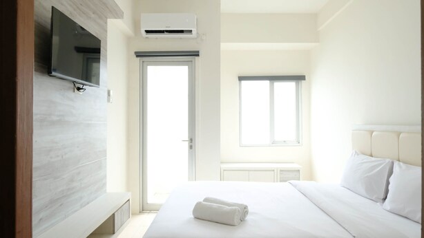 Une chambre d’hôtel équipée d’un lit, d’un téléviseur fixé au mur, d’un appareil de climatisation, d’une fenêtre et d’une porte.