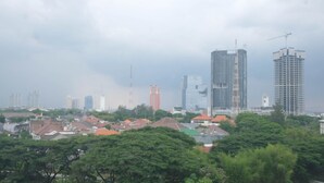 Un paysage urbain avec de hauts immeubles, dont certains sont en construction, et des maisons d’habitation aux toits rouges.