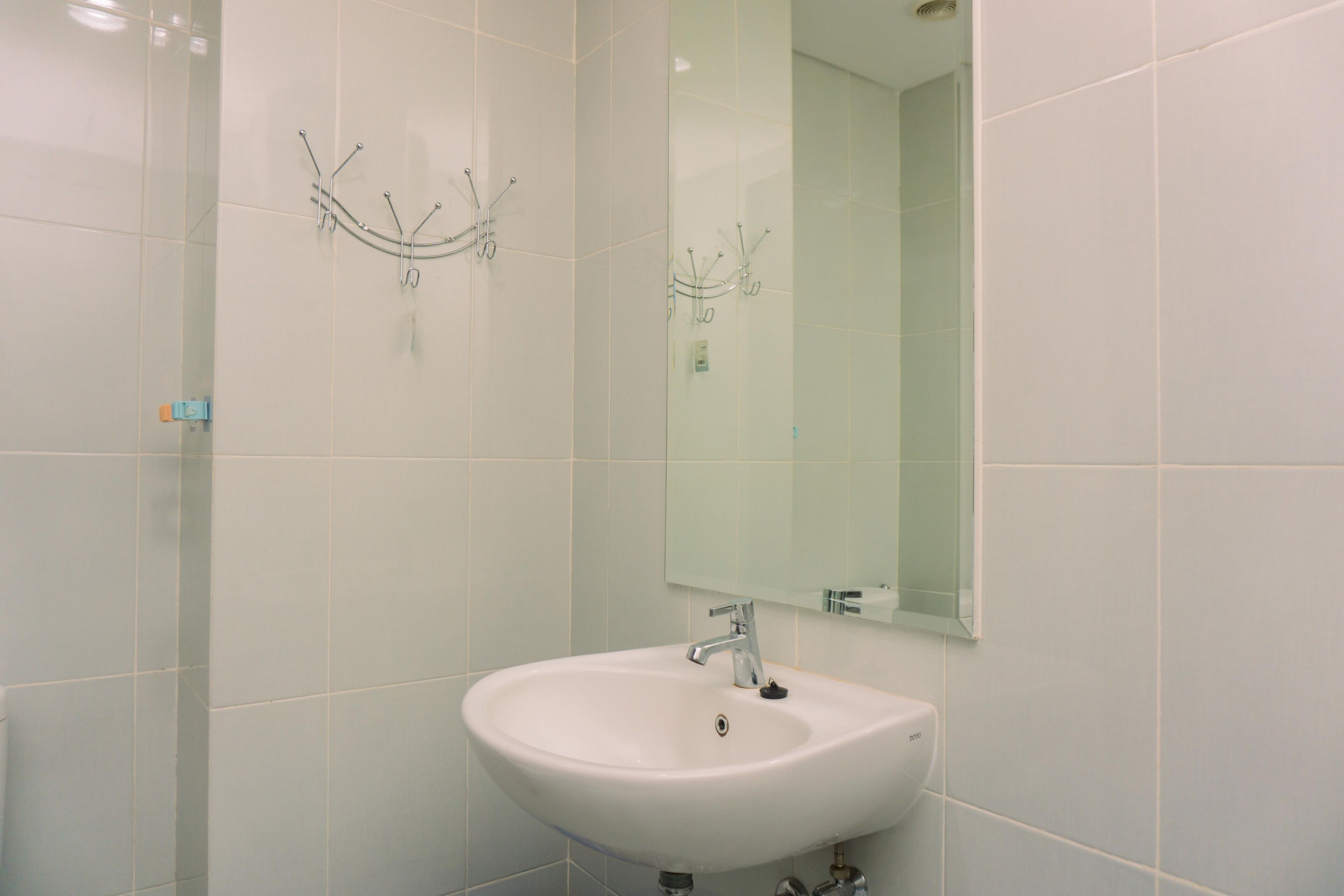 A bathroom with white tiles, a white sink, and a mirror.