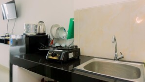 A kitchen with a sink, a stove, and a dish rack. - Studio With Comfortable Design At Serpong Garden Apartment (Cisauk)