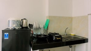 A compact kitchen with a refrigerator, a stove, a sink, and a dish rack. - Studio With Comfortable Design At Serpong Garden Apartment (Cisauk)