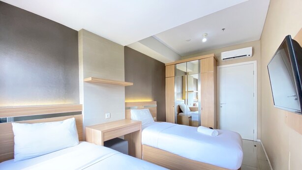 Une chambre d’hôtel avec deux lits, un bureau, un miroir et un appareil de climatisation.