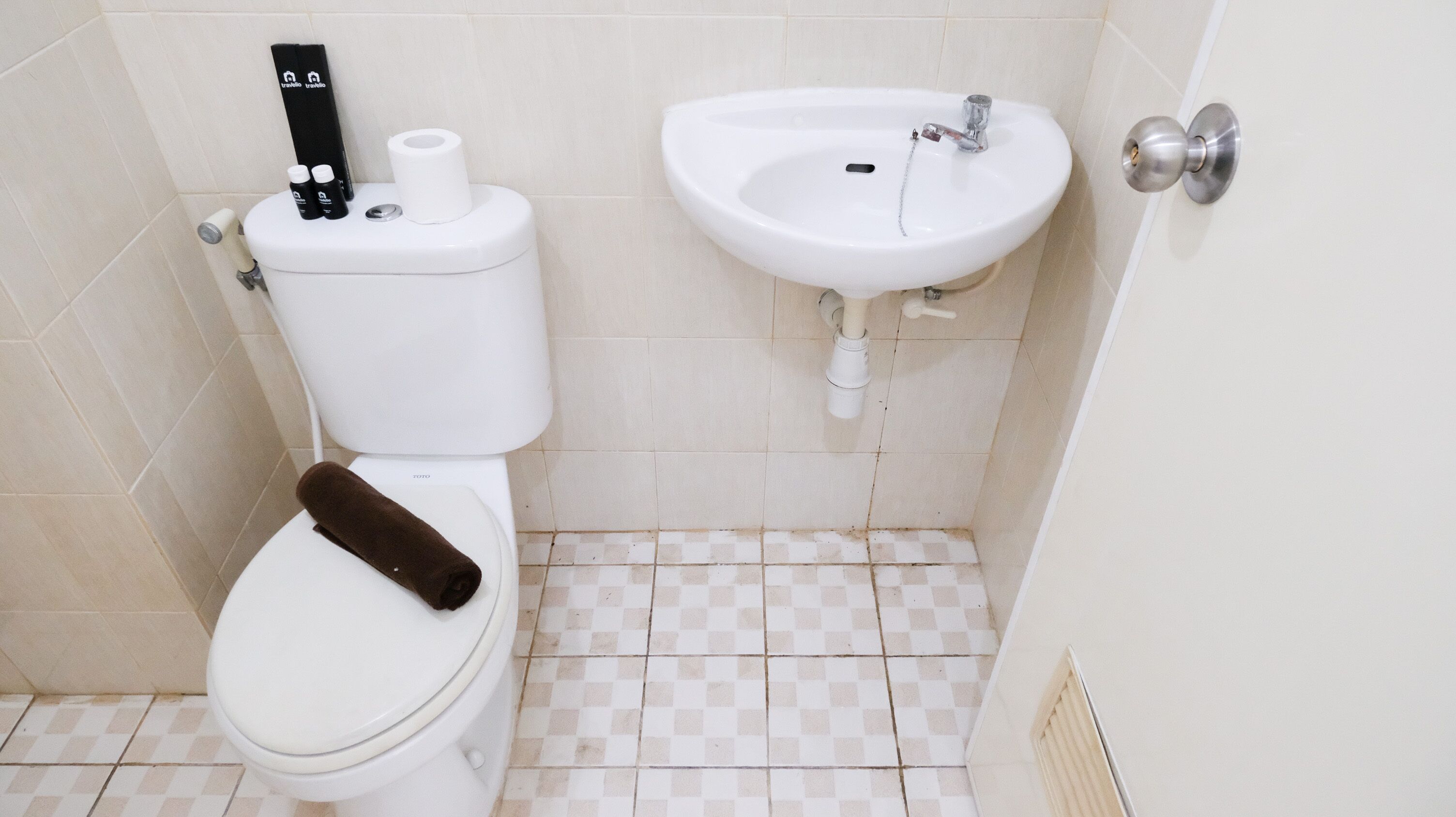 Kylpyhuone, jossa on wc, pesuallas ja pyyhe istuimella.