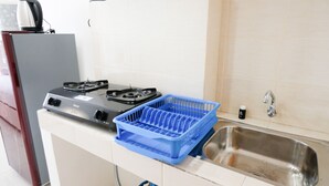 Une cuisine équipée d’une cuisinière à gaz, d’un récipient en plastique bleu et d’un évier en acier inoxydable.