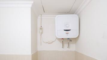 A white water heater mounted on a wall with a control panel and two pipes.