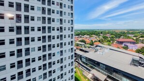 Un edificio alto con una fachada de ventanas y balcones, y vistas a un pueblo con diversos edificios y zonas verdes.