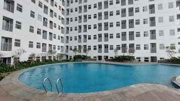 A modern building with a central swimming pool surrounded by a wooden deck.