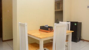 A small kitchen with a wooden table and white chairs, a black refrigerator, and a cabinet above the sink. - Elegant And Nice 2Br At Grand Palace Kemayoran Apartment (Jakarta)