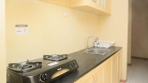A kitchen with a gas stove, a sink, and a cabinet above the counter. - Elegant And Nice 2Br At Grand Palace Kemayoran Apartment (Jakarta)