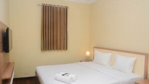 A hotel room with a bed, a TV mounted on the wall, a nightstand with a lamp, and a window with curtains. - Elegant And Nice 2Br At Grand Palace Kemayoran Apartment (Jakarta)