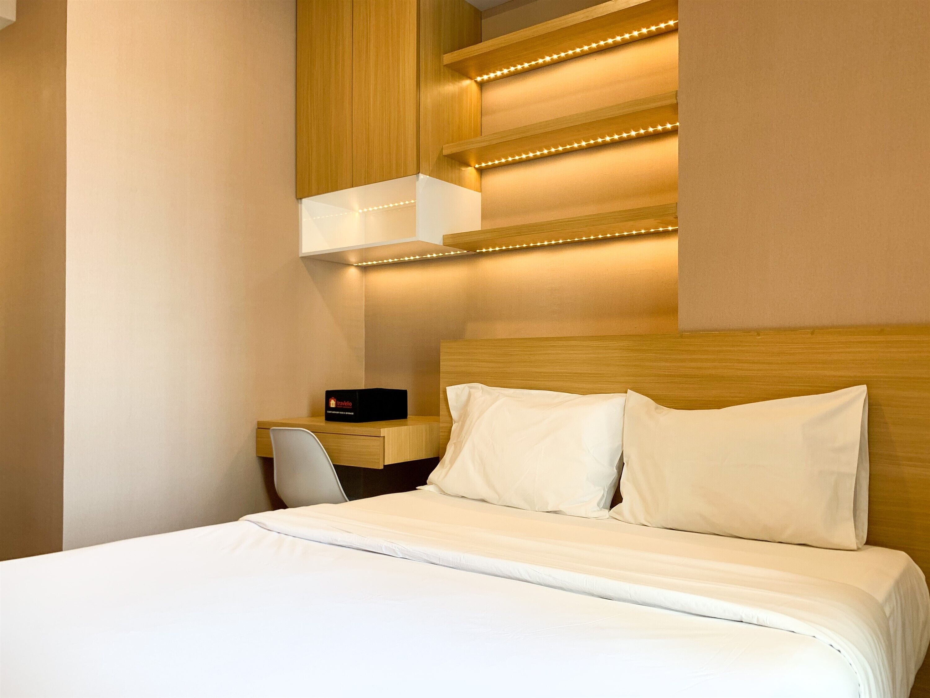 A neatly made bed with white linens in a modern hotel room.