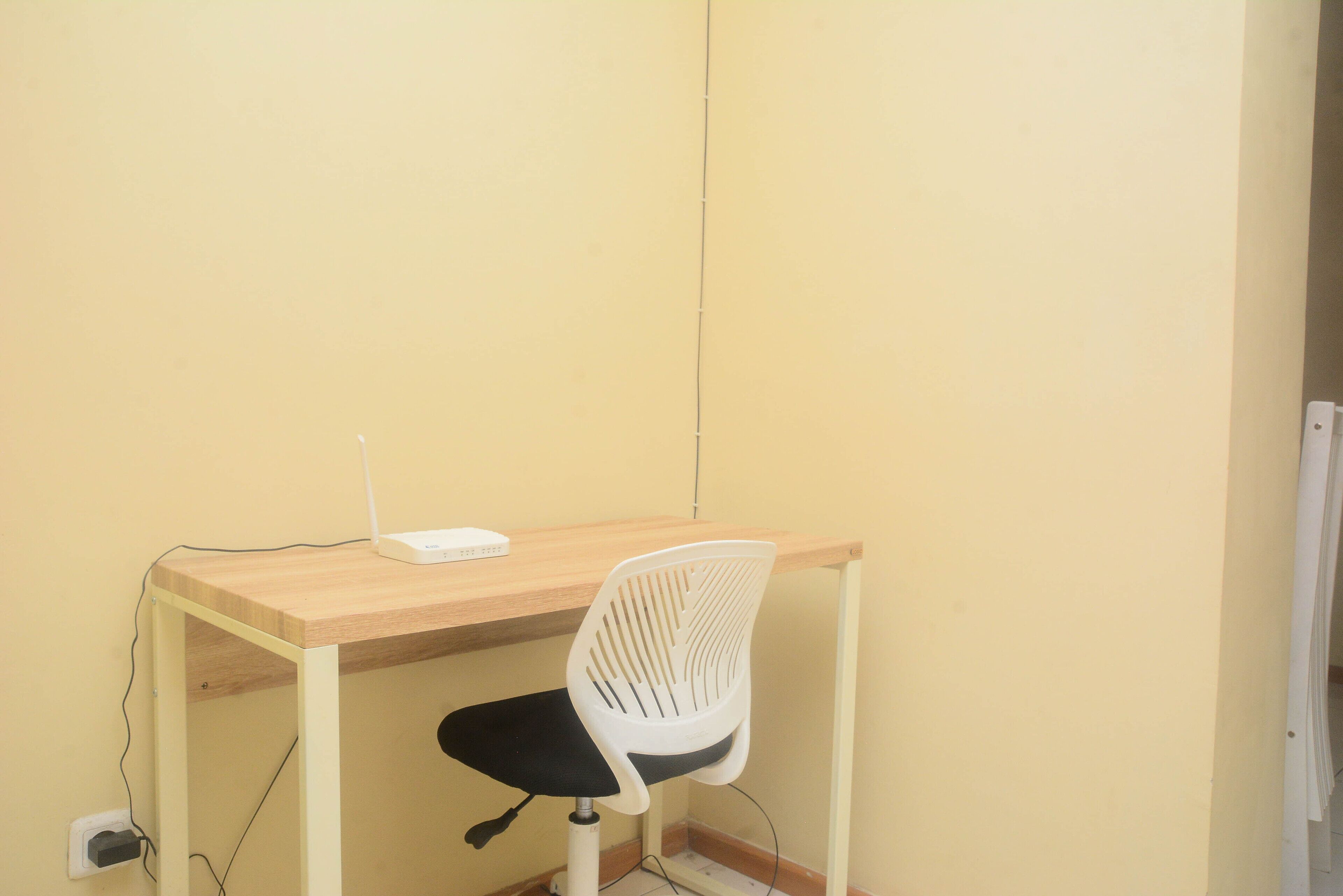Un espacio de trabajo pequeño y sencillo con un escritorio de madera y una silla blanca.
