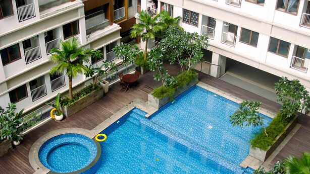 Ein Pool auf dem Dach mit einem runden Whirlpool, umgeben von Topfpflanzen und einer Holzterrasse.