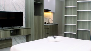 Ein modernes Hotelzimmer mit einem großen Bett, einem Flachbildfernseher, einer integrierten Küche mit Spüle und einem kleinen Badezimmer.