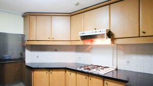 A kitchen with wooden cabinets, a stainless steel refrigerator, and a gas stove. - Extra Spacious And Homey 2Br At Kondominium Puncak Marina Apartment (Surabaya)
