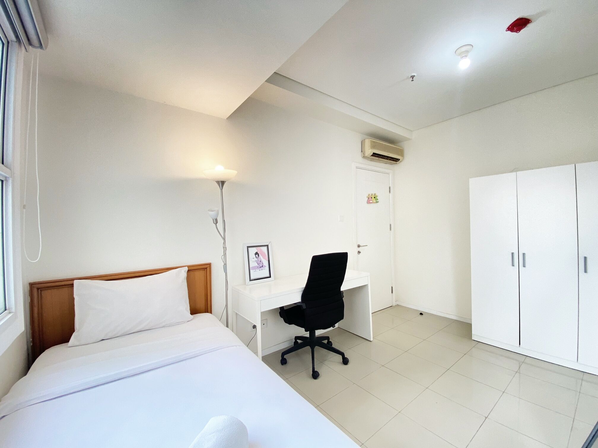 Une chambre d’hôtel avec un lit, un bureau, une chaise et une armoire.