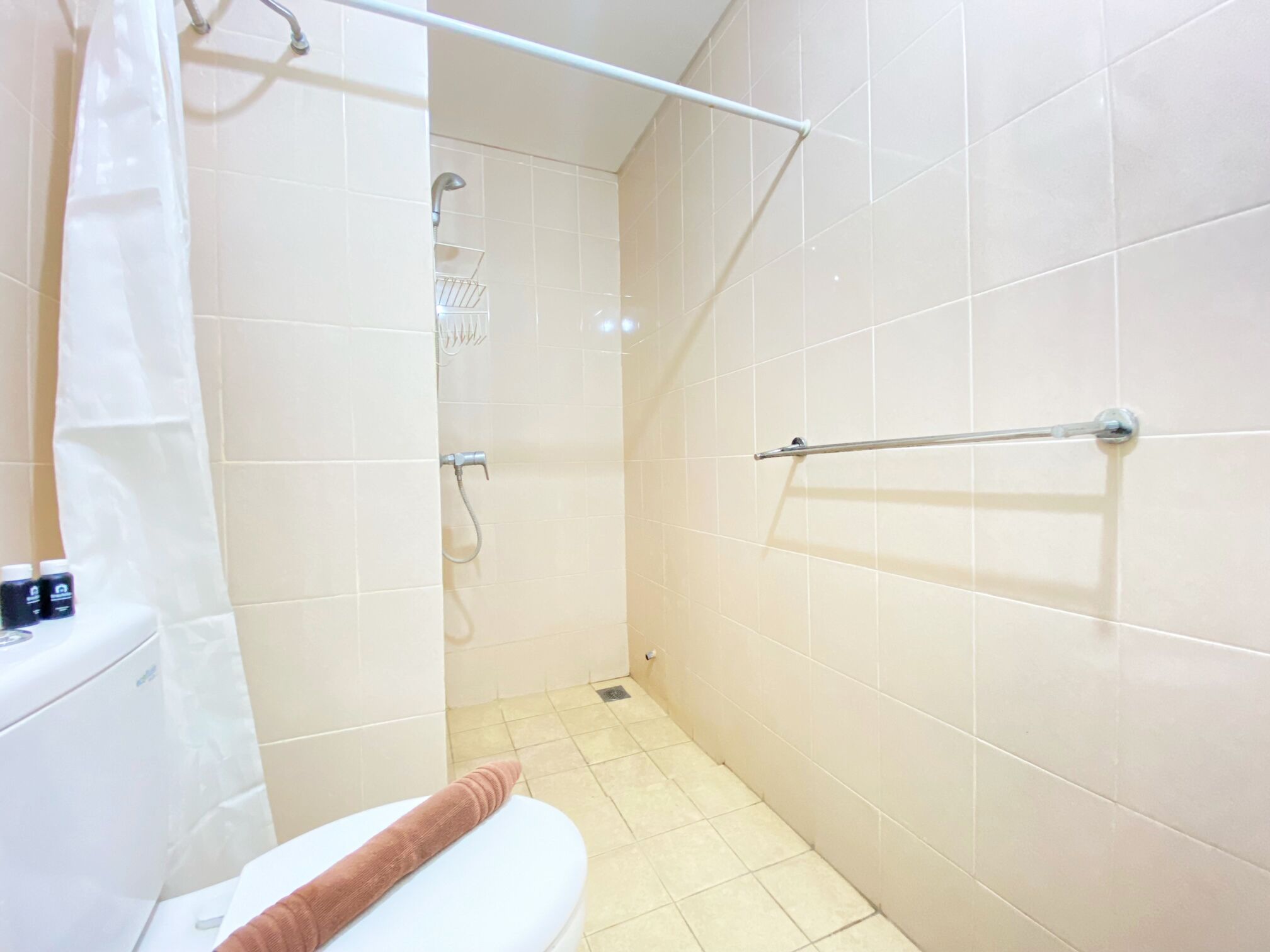 Une salle de bain équipée de toilettes, d’une douche et d’un porte-serviettes.