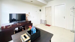 Una sala de estar moderna con televisor de pantalla plana, muebles de madera oscura, una mesa de centro con una caja decorativa y un portavasos para botella de agua.
