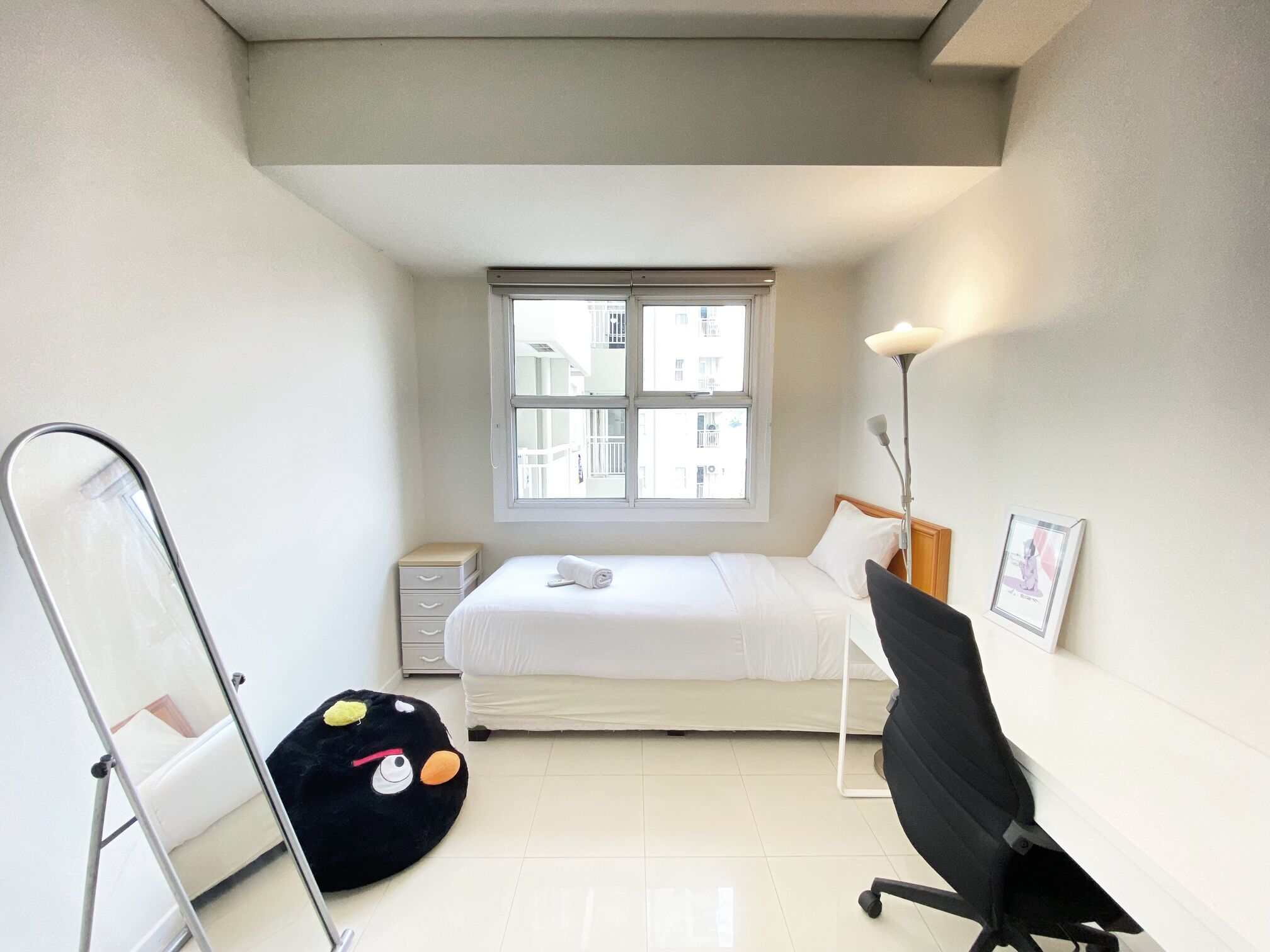Un dormitorio pequeño y moderno con una cama, un escritorio, una silla, un ventanal y un sillón de girable negro.