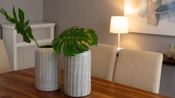 Two textured vases with green leaves on a wooden table.