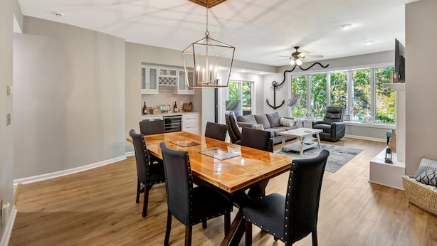 A spacious living area with a wooden dining table, black chairs, a sofa, and a ceiling fan.