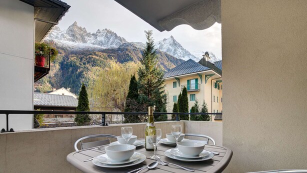 Ein Balkon mit Esstisch, mit Blick auf eine Berglandschaft.