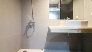 A modern bathroom with a shower, sink, and mirror. - New Studio At Patraland Amarta Apartment (Ngaglik)