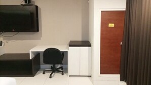 A small, clean room with a desk, chair, and a television mounted on the wall. - Luxurious Studio At Mataram City Apartment (Ngaglik)