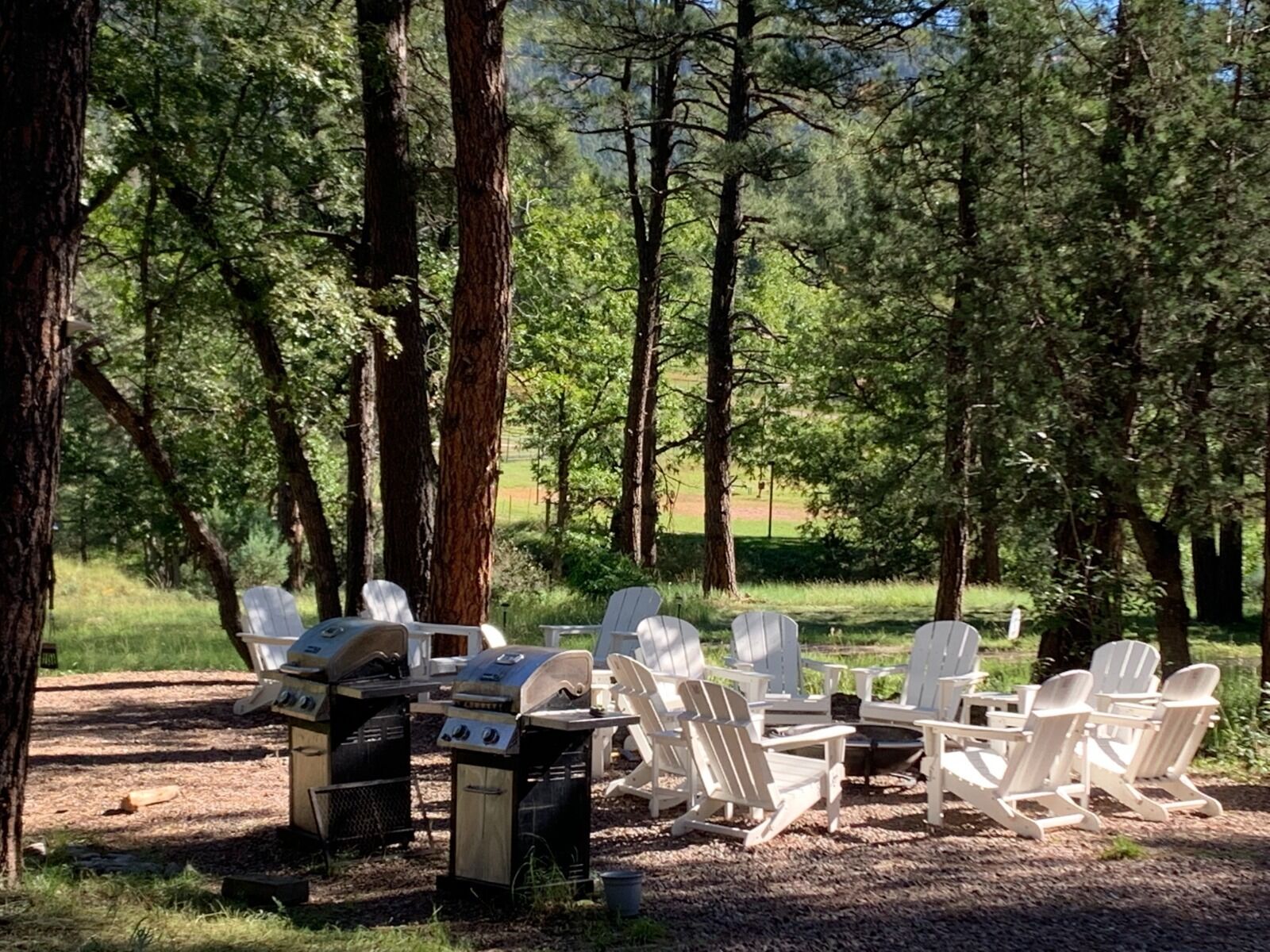 Un espacio al aire libre con sillas Adirondack y una parrilla.